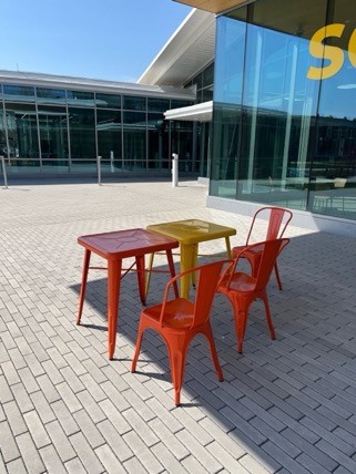 A table and chairs outside of a building Description automatically generated