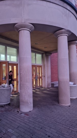 A person standing in front of a building Description automatically generated