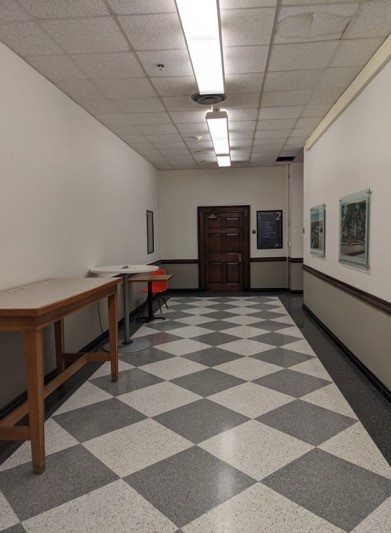 A long hallway with a table and chairs Description automatically generated