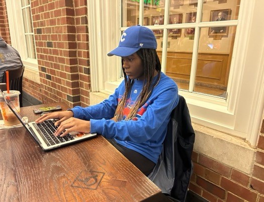 A person sitting at a table using a computer Description automatically generated