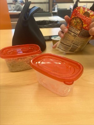 A hand holding a package of food Description automatically generated